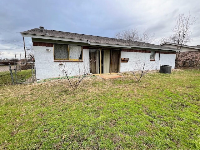 rear view of house with brick siding, fence, cooling unit, and a yard