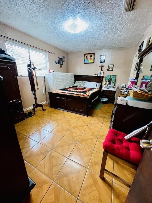 bedroom with a textured ceiling, light tile patterned flooring, visible vents, and baseboards