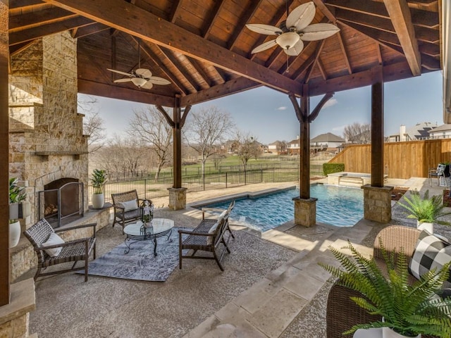 view of patio / terrace with a gazebo, an outdoor stone fireplace, a fenced backyard, and a fenced in pool