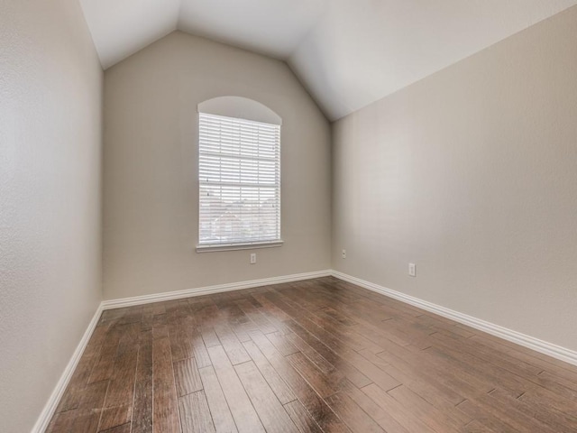 unfurnished room featuring lofted ceiling, baseboards, and wood finished floors