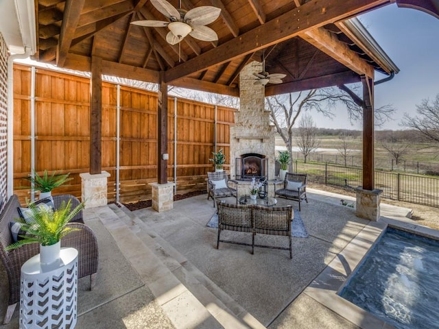 view of patio / terrace with a gazebo, an outdoor living space with a fireplace, fence, and a ceiling fan