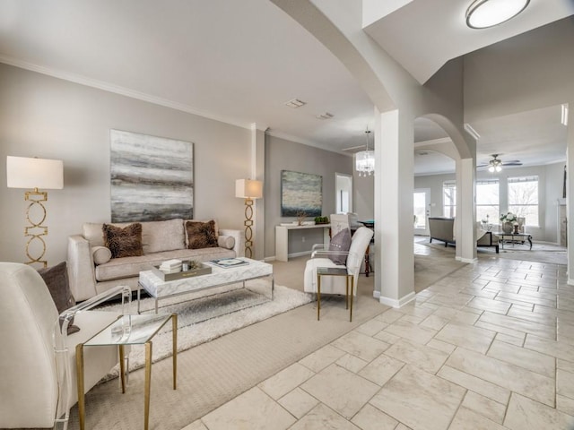 living area with baseboards, ceiling fan with notable chandelier, arched walkways, and ornamental molding