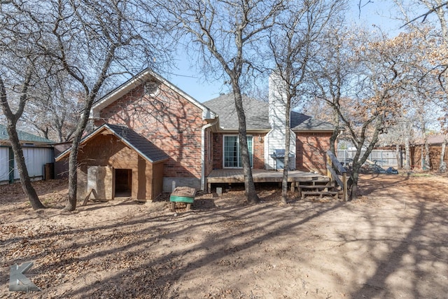 exterior space featuring brick siding, roof with shingles, fence, a deck, and stone siding