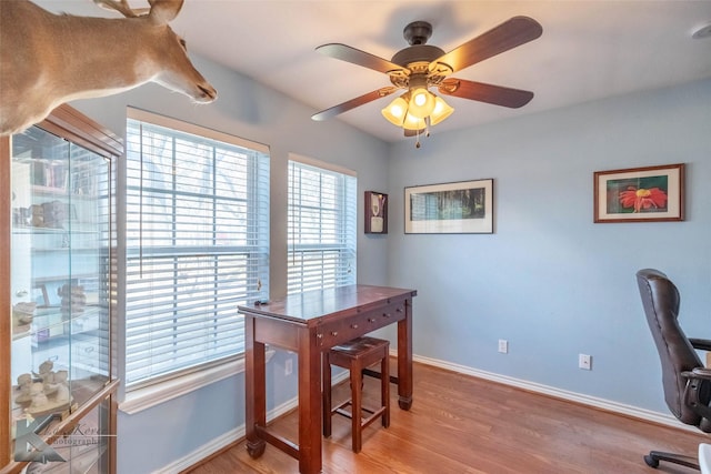 office area featuring a ceiling fan, light wood-style flooring, and baseboards