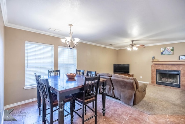 dining space featuring a tiled fireplace, baseboards, and crown molding