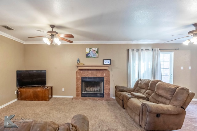 living room with baseboards, visible vents, a tiled fireplace, a ceiling fan, and ornamental molding