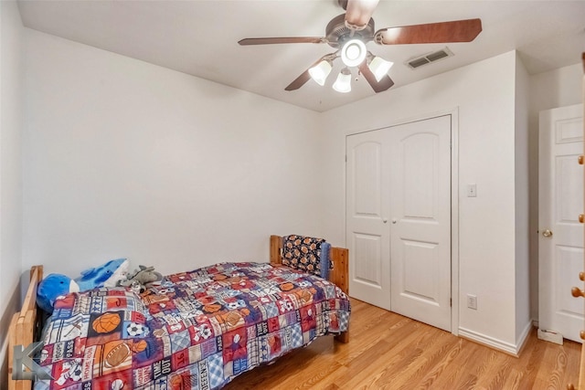 bedroom with light wood finished floors, visible vents, baseboards, ceiling fan, and a closet