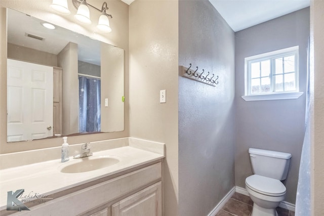 bathroom with toilet, vanity, baseboards, visible vents, and tile patterned floors