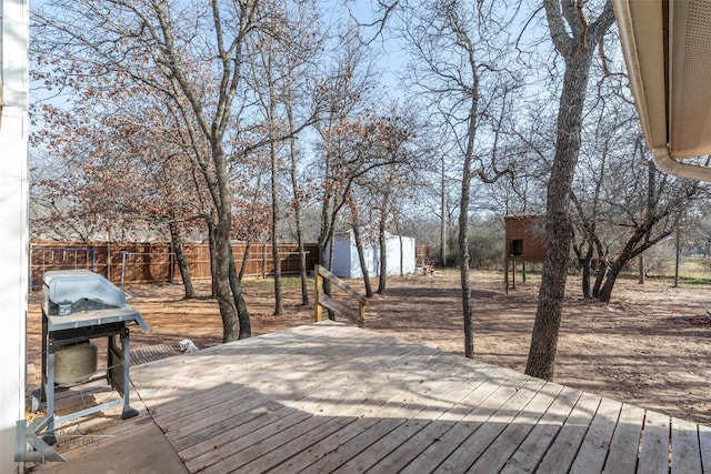 deck featuring a storage unit, grilling area, an outdoor structure, and fence