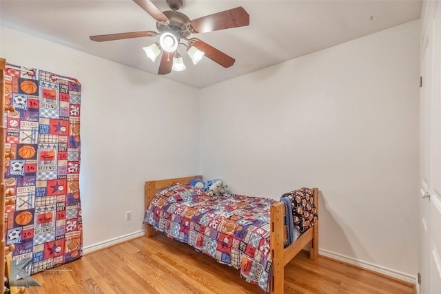 bedroom featuring a ceiling fan, baseboards, and wood finished floors