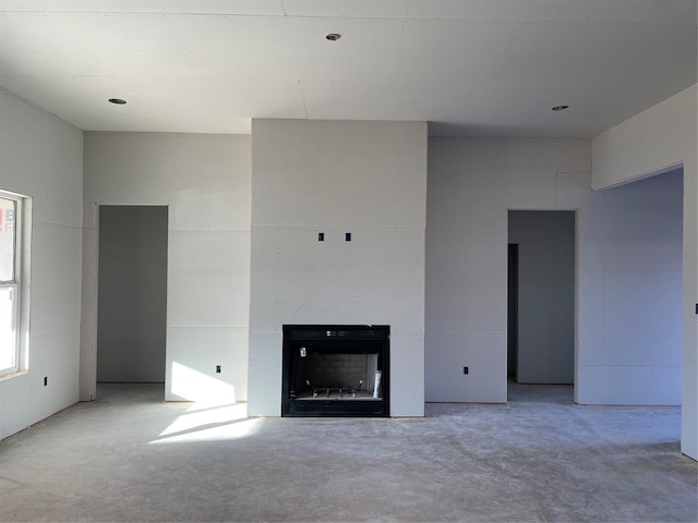 unfurnished living room featuring a fireplace and unfinished concrete floors