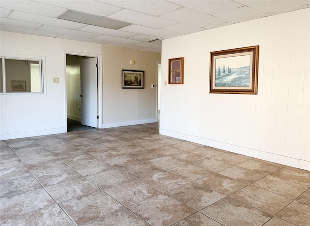 unfurnished room featuring baseboards and a drop ceiling