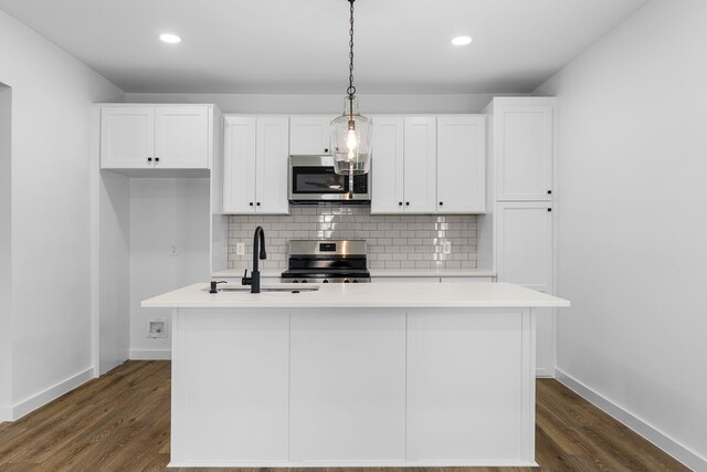 kitchen featuring white cabinets, decorative backsplash, appliances with stainless steel finishes, a kitchen island with sink, and light countertops