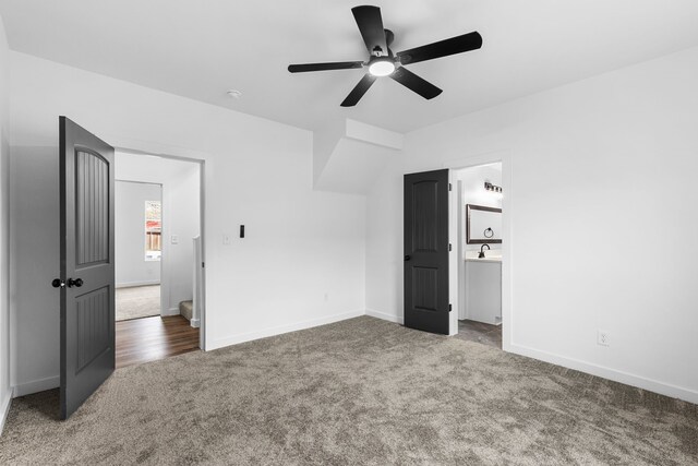 unfurnished bedroom with carpet, a sink, a ceiling fan, and baseboards