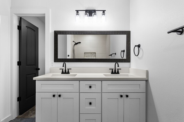bathroom featuring double vanity, a sink, and tiled shower