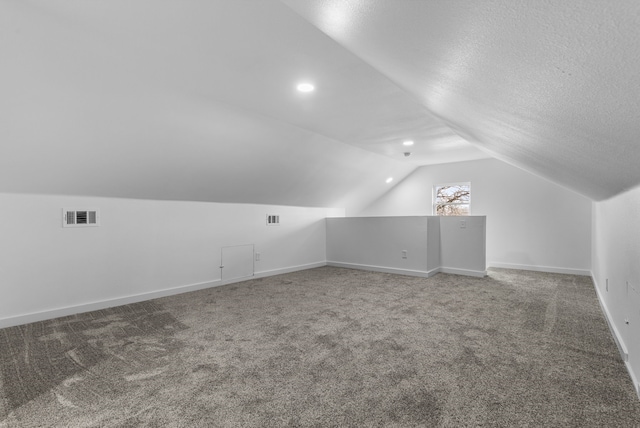 bonus room featuring a textured ceiling, visible vents, baseboards, vaulted ceiling, and carpet