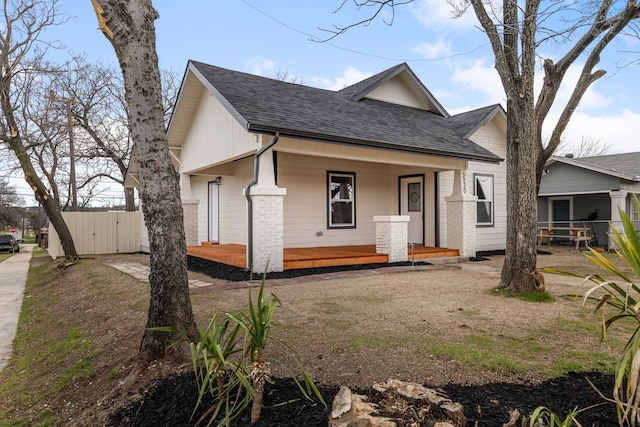 rear view of house featuring covered porch, a shingled roof, a gate, and fence