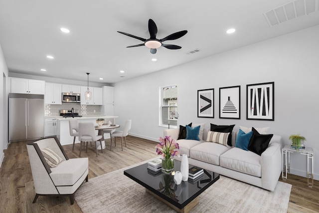 living room featuring a ceiling fan, recessed lighting, visible vents, and wood finished floors