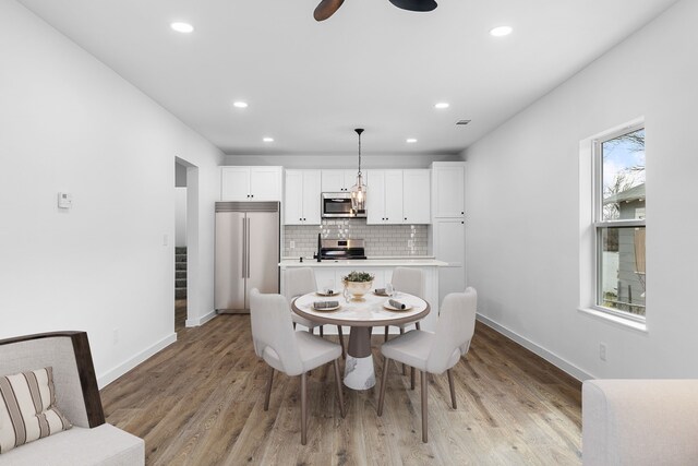 dining area with a ceiling fan, recessed lighting, light wood-style flooring, and baseboards