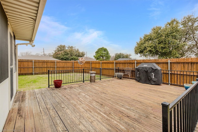 deck with a grill, a fenced backyard, and a yard