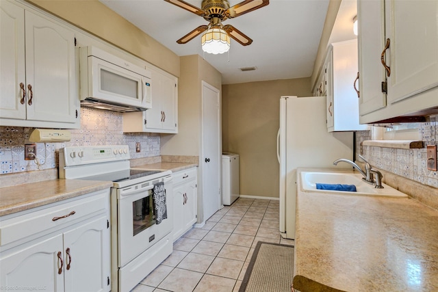 kitchen featuring light tile patterned floors, white appliances, a sink, white cabinets, and backsplash