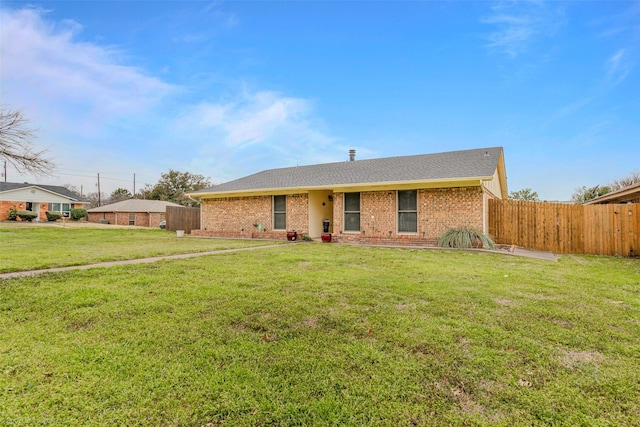 single story home featuring a shingled roof, brick siding, fence, and a front lawn