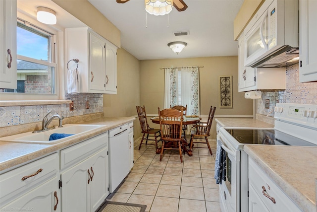 kitchen with white appliances, light tile patterned floors, decorative backsplash, white cabinets, and a sink