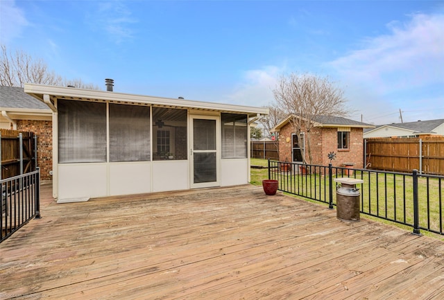 wooden deck featuring a sunroom, a fenced backyard, a lawn, and an outdoor structure