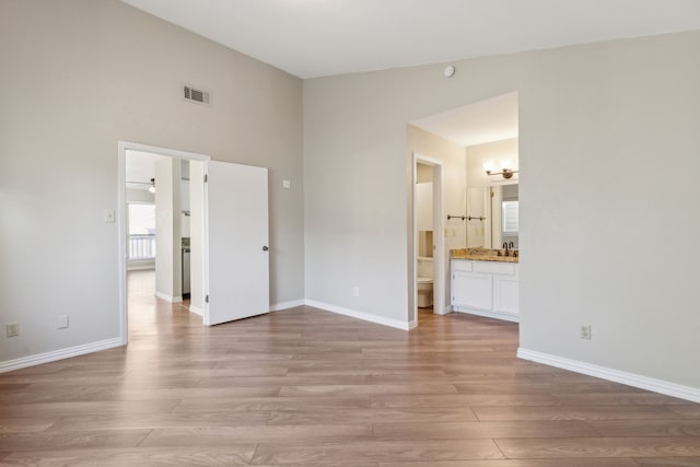 unfurnished bedroom with light wood-type flooring, visible vents, baseboards, and a sink