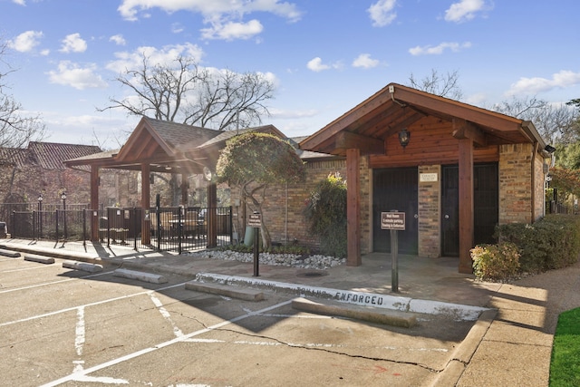 view of building exterior with uncovered parking and fence