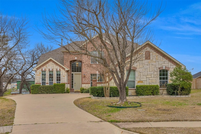 view of front of property with driveway, brick siding, stone siding, and a front yard