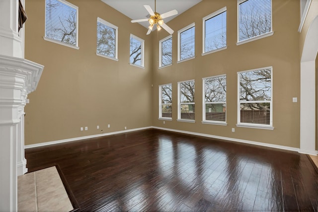 unfurnished living room with wood-type flooring, decorative columns, baseboards, and ceiling fan