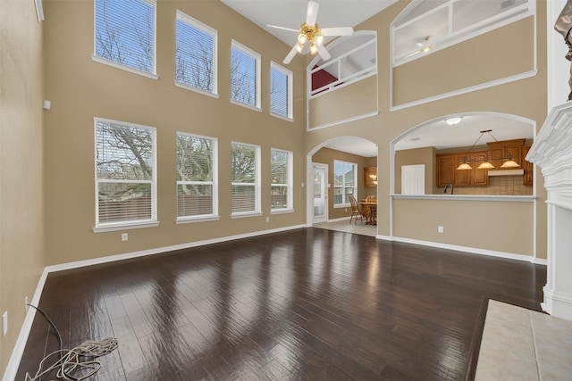 unfurnished living room featuring a ceiling fan, baseboards, and hardwood / wood-style floors