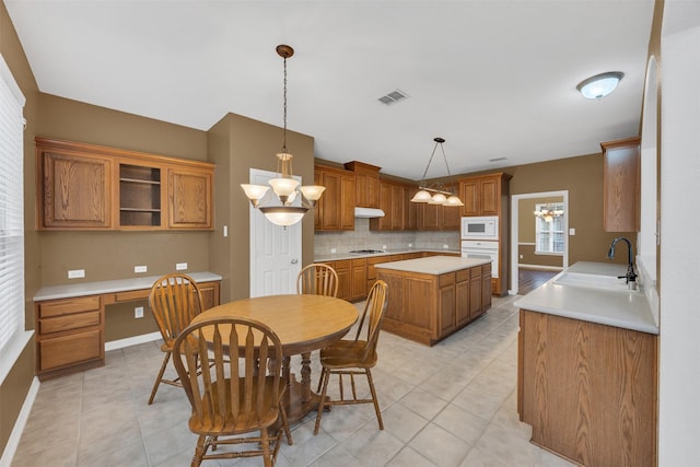 interior space with white appliances, visible vents, backsplash, built in desk, and a sink