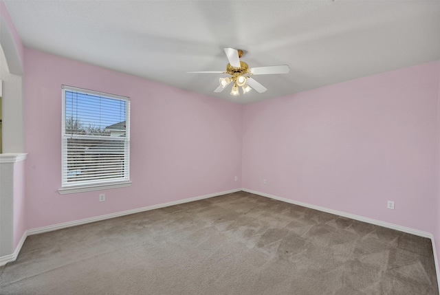 carpeted spare room featuring a ceiling fan and baseboards