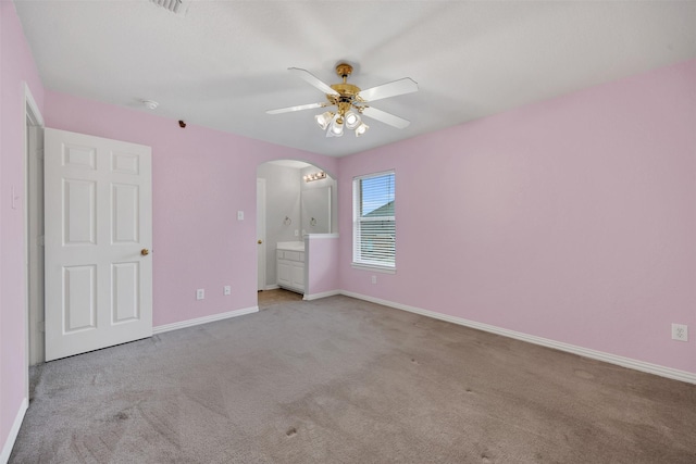 unfurnished bedroom featuring arched walkways, carpet flooring, a ceiling fan, and baseboards