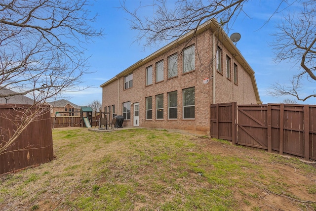 rear view of property with a lawn, a fenced backyard, a gate, a patio area, and a playground