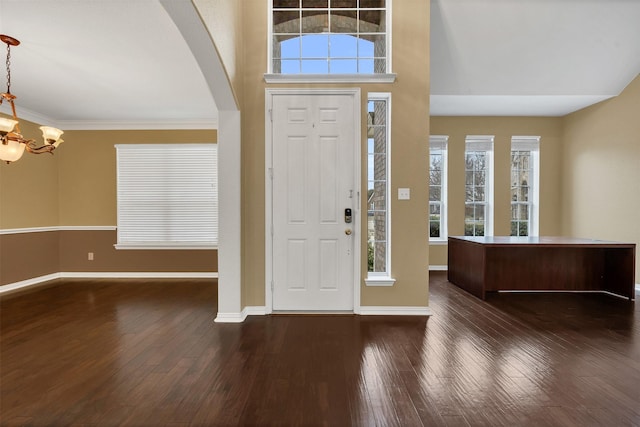 foyer featuring dark wood-style floors, baseboards, arched walkways, and an inviting chandelier