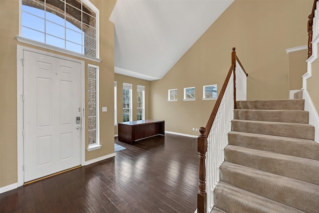 entryway with stairway, baseboards, high vaulted ceiling, and dark wood-type flooring