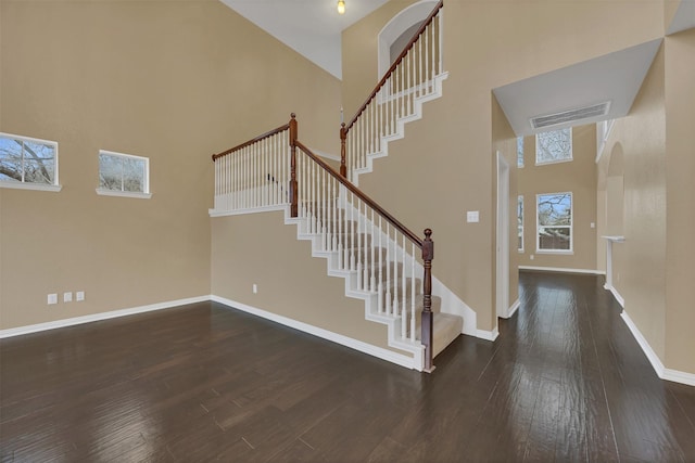 entryway featuring a high ceiling, dark wood-style flooring, visible vents, baseboards, and stairway