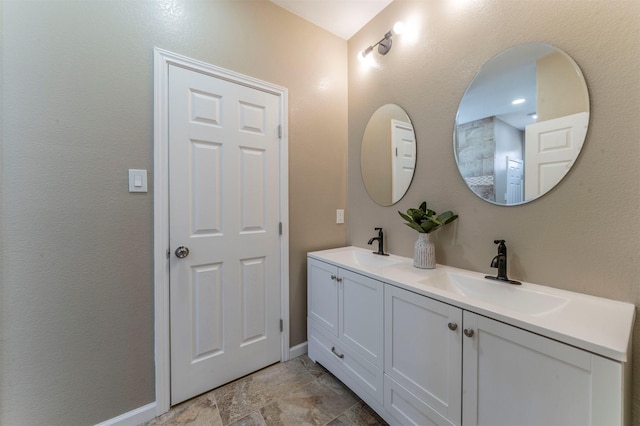 bathroom with a sink, baseboards, and double vanity