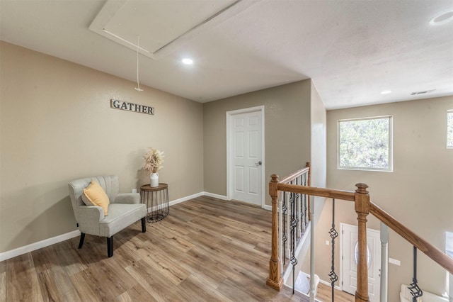 living area featuring wood finished floors, an upstairs landing, attic access, and baseboards