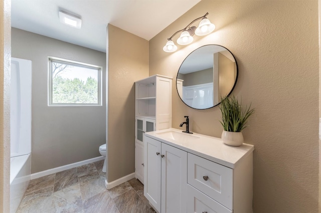 bathroom with toilet, vanity, and baseboards