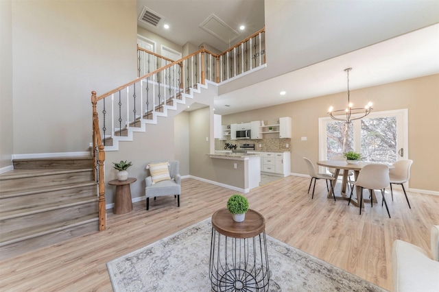 dining room featuring light wood-style floors, baseboards, visible vents, and a chandelier