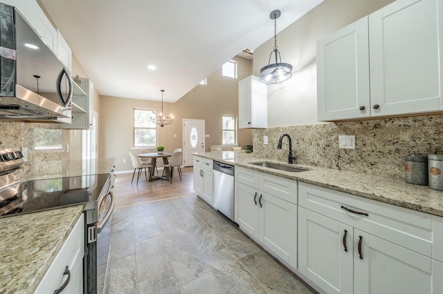 kitchen with stainless steel appliances, a sink, white cabinetry, tasteful backsplash, and decorative light fixtures