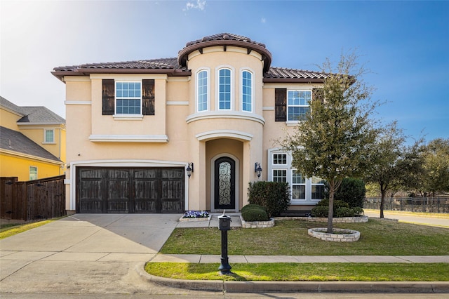 mediterranean / spanish-style home featuring a front lawn, stucco siding, an attached garage, and fence
