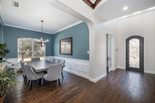 dining area with crown molding, arched walkways, a notable chandelier, and wood finished floors