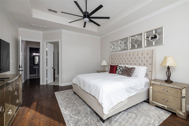 bedroom with a tray ceiling, dark wood-style flooring, and visible vents