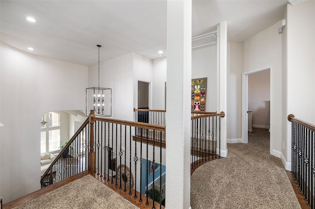 hallway featuring baseboards, arched walkways, an inviting chandelier, carpet flooring, and an upstairs landing