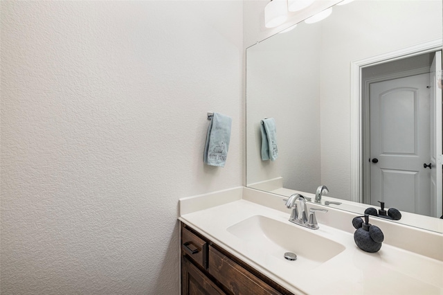 bathroom with a textured wall and vanity